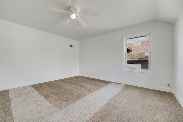 spare room featuring visible vents, carpet floors, baseboards, ceiling fan, and vaulted ceiling