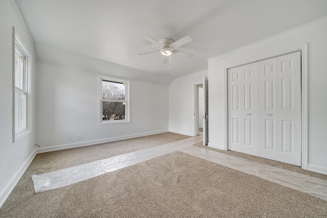 unfurnished bedroom with baseboards, ceiling fan, light colored carpet, lofted ceiling, and a closet