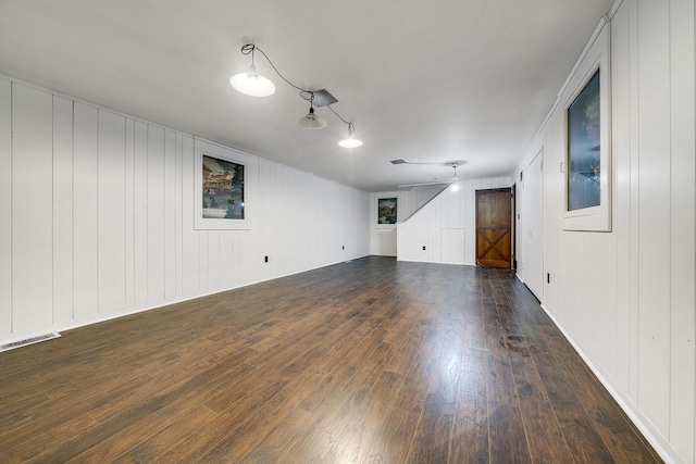 spare room with dark wood finished floors, visible vents, and a barn door