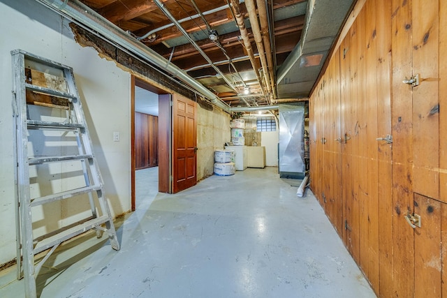 unfinished below grade area featuring heating unit and washer / dryer