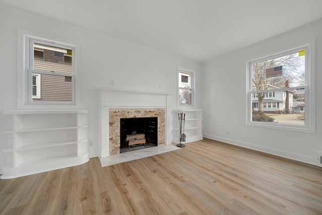 unfurnished living room with a fireplace, wood finished floors, and baseboards