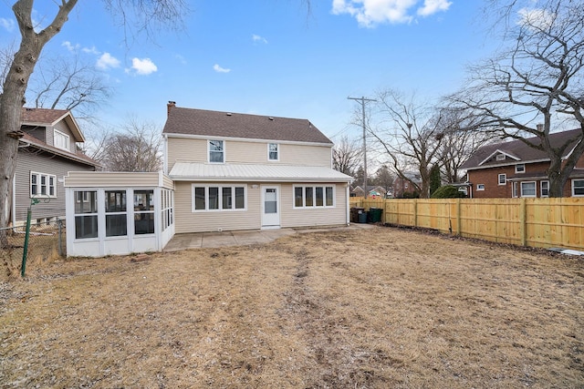 back of house featuring a patio area, a chimney, a fenced backyard, and a sunroom