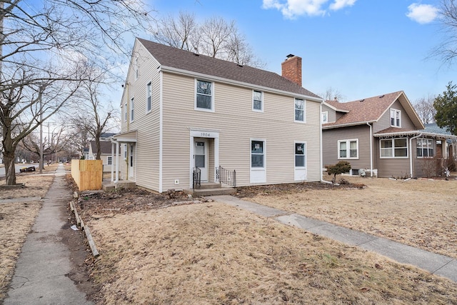 rear view of property with a chimney and a shingled roof