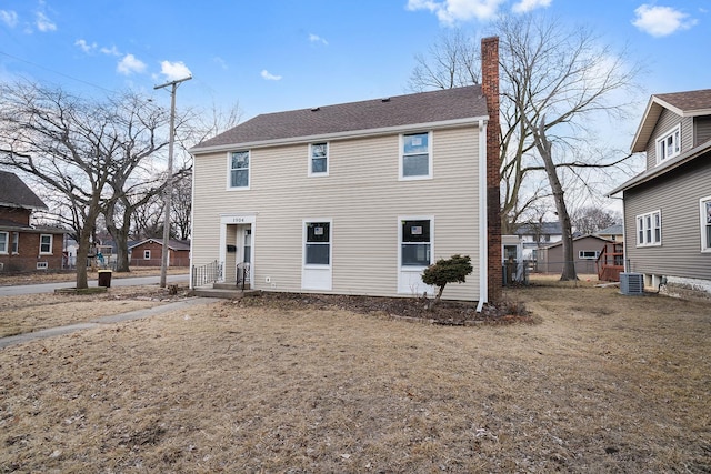 back of property featuring central AC unit, a chimney, and fence