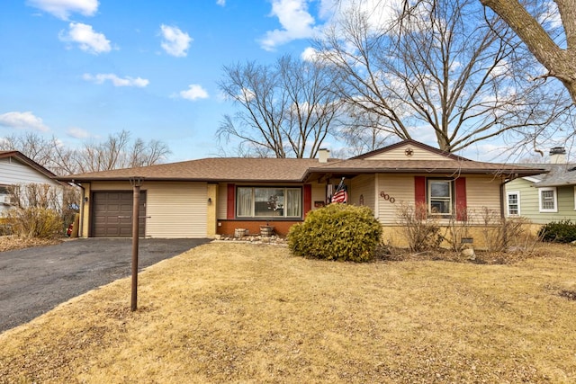 single story home with aphalt driveway, brick siding, a chimney, an attached garage, and a front lawn