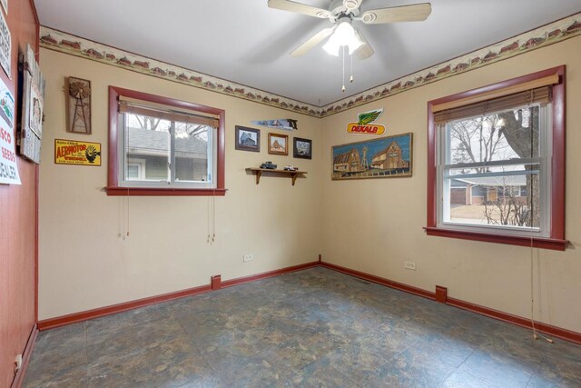 empty room with ceiling fan and baseboards