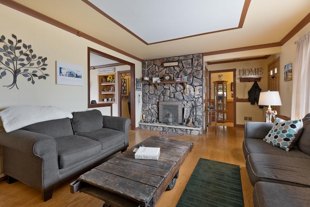 living room featuring visible vents, a stone fireplace, and wood finished floors