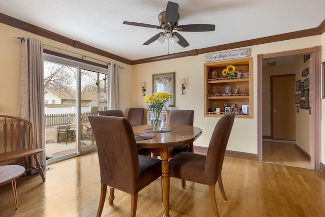 dining room with baseboards, ornamental molding, a ceiling fan, and light wood-style floors