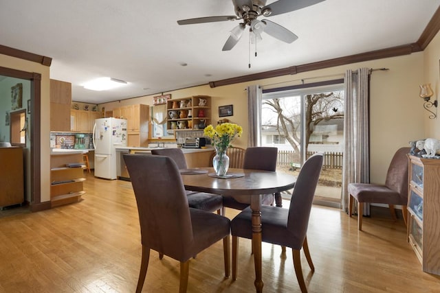 dining area featuring light wood-style floors, ornamental molding, and a ceiling fan