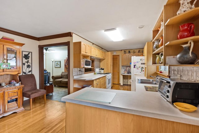 kitchen featuring a toaster, light countertops, a sink, light wood-type flooring, and white appliances