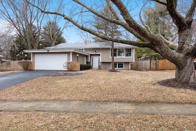 view of front of house featuring driveway, a chimney, an attached garage, and fence