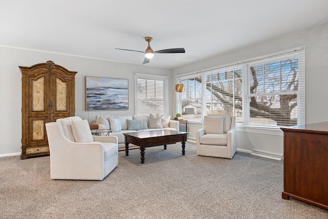 living area with light colored carpet, ceiling fan, and baseboards