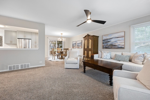 living room featuring carpet floors, plenty of natural light, visible vents, and ceiling fan with notable chandelier