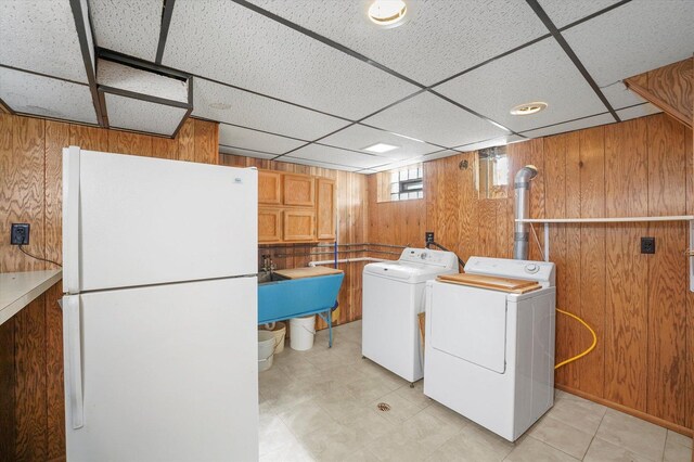 laundry room featuring a sink, laundry area, washing machine and dryer, and wooden walls