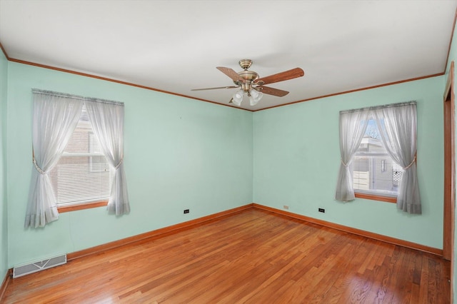 spare room featuring visible vents, crown molding, baseboards, and wood finished floors