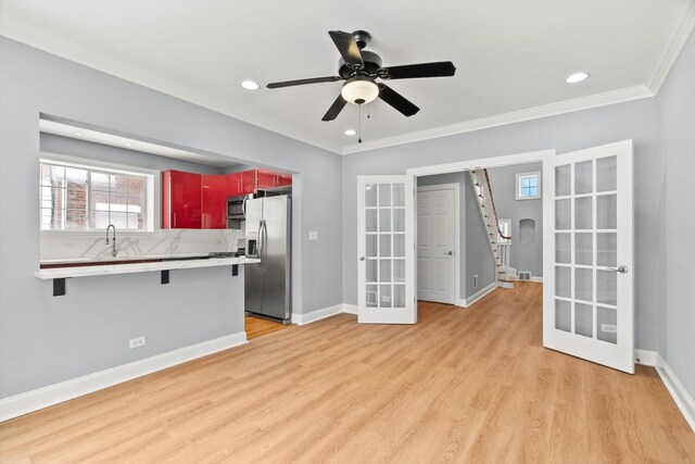 kitchen with baseboards, appliances with stainless steel finishes, french doors, light wood-type flooring, and a kitchen bar