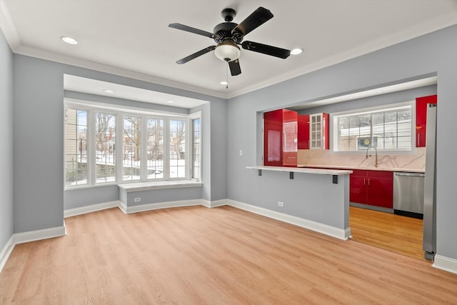 interior space featuring light wood finished floors, appliances with stainless steel finishes, a wealth of natural light, and ornamental molding