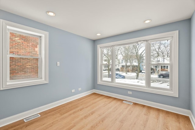 spare room featuring light wood-style floors, baseboards, and visible vents