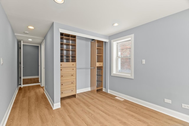 unfurnished bedroom featuring a closet, recessed lighting, light wood-style flooring, and baseboards