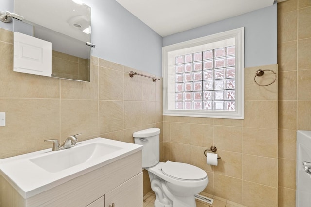 full bathroom featuring tile patterned flooring, tile walls, toilet, and vanity