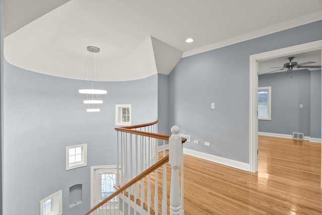 hall with wood finished floors, visible vents, an upstairs landing, baseboards, and a wealth of natural light