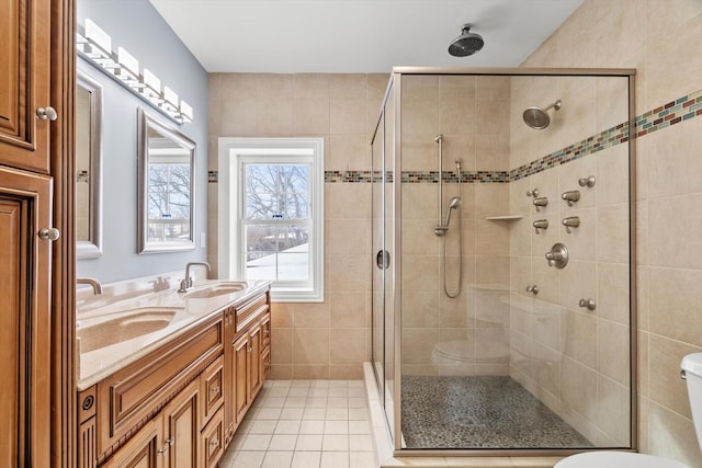 bathroom with a stall shower, a sink, toilet, and tile patterned floors