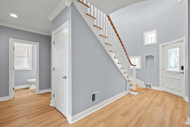 entryway with crown molding, a wealth of natural light, visible vents, light wood-style flooring, and baseboards