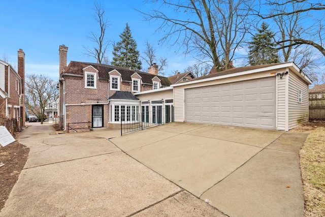 view of front of house featuring a garage, a chimney, fence, an outdoor structure, and brick siding