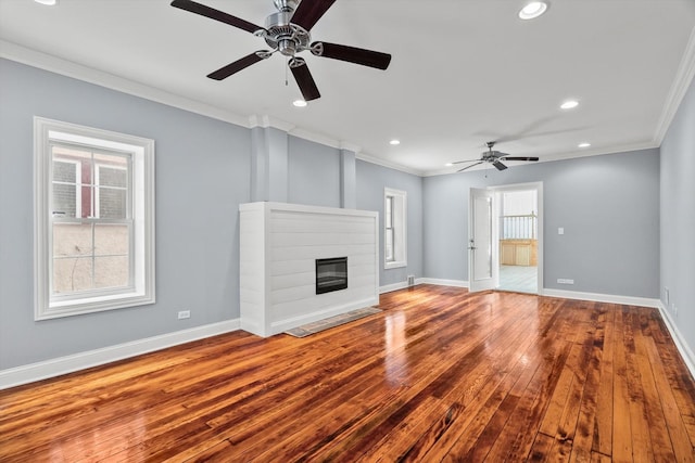 unfurnished living room featuring ornamental molding, a glass covered fireplace, and baseboards