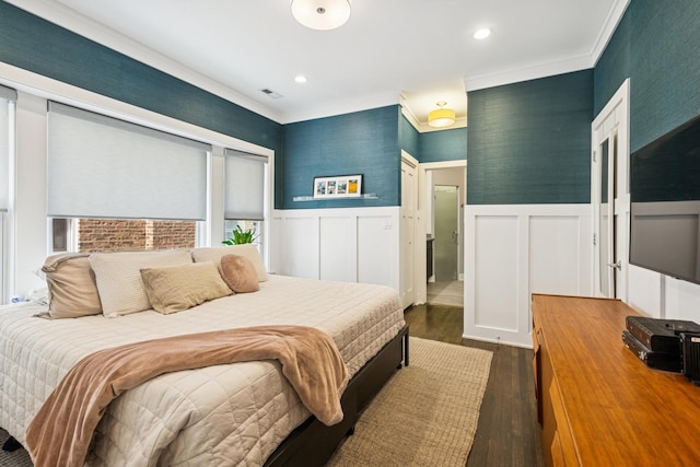 bedroom featuring dark wood-type flooring, wainscoting, visible vents, and wallpapered walls