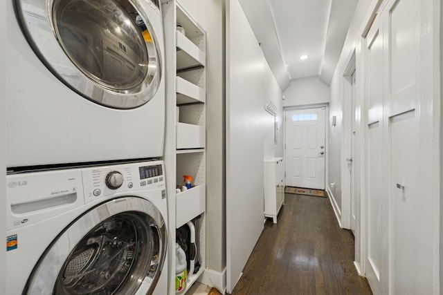 washroom featuring stacked washer and dryer, laundry area, baseboards, and wood finished floors