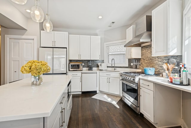 kitchen featuring dishwasher, wall chimney exhaust hood, stainless steel stove, fridge, and a sink