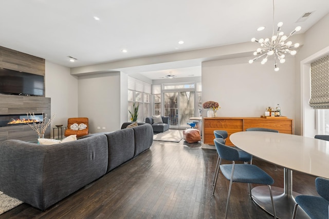 living area with visible vents, a tiled fireplace, wood-type flooring, an inviting chandelier, and recessed lighting