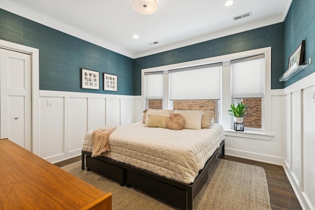 bedroom with dark wood-type flooring, wainscoting, visible vents, and a decorative wall