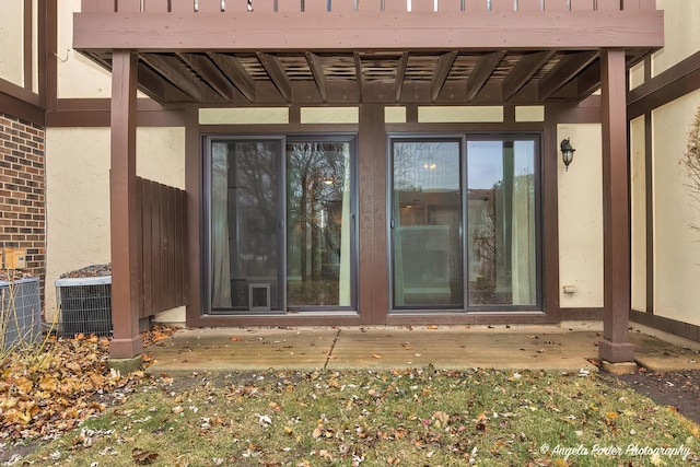 entrance to property featuring central AC, brick siding, and stucco siding