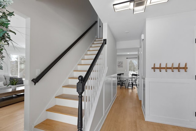 stairs featuring wood finished floors and a healthy amount of sunlight