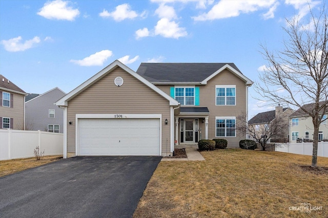 traditional-style house featuring driveway, an attached garage, fence, and a front yard