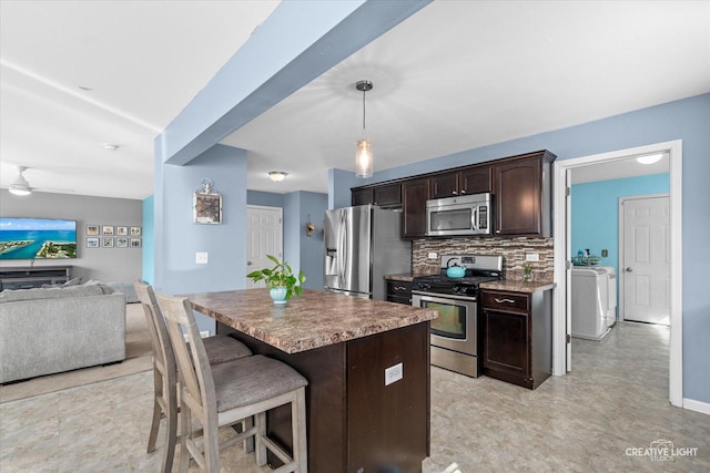 kitchen featuring tasteful backsplash, a breakfast bar area, open floor plan, stainless steel appliances, and dark brown cabinets