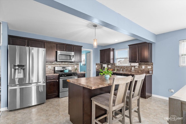 kitchen featuring dark brown cabinets, appliances with stainless steel finishes, a breakfast bar, and decorative backsplash