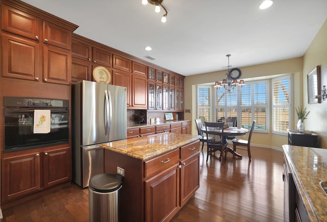 kitchen featuring light stone counters, visible vents, dark wood finished floors, freestanding refrigerator, and oven