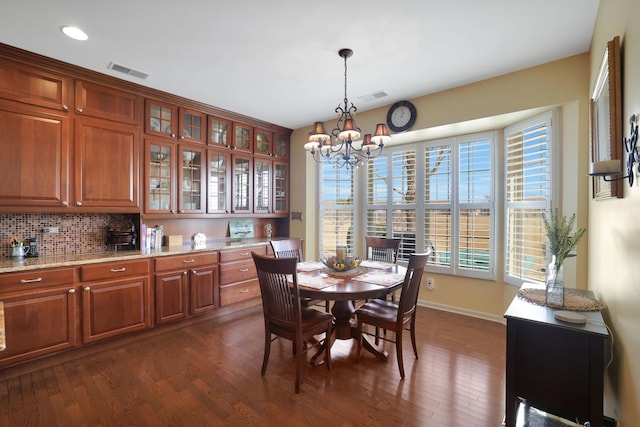 dining area featuring dark wood finished floors, an inviting chandelier, baseboards, and visible vents