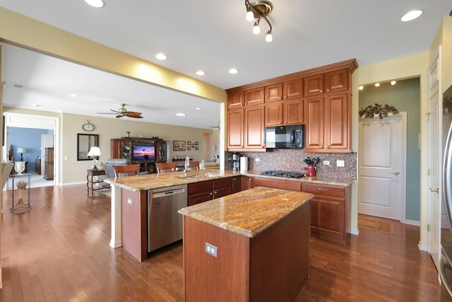 kitchen featuring a sink, tasteful backsplash, open floor plan, appliances with stainless steel finishes, and a peninsula