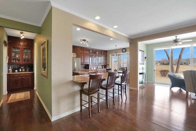 kitchen featuring decorative backsplash, a peninsula, baseboards, and freestanding refrigerator