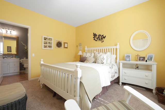 bedroom with ensuite bathroom, baseboards, and carpet floors