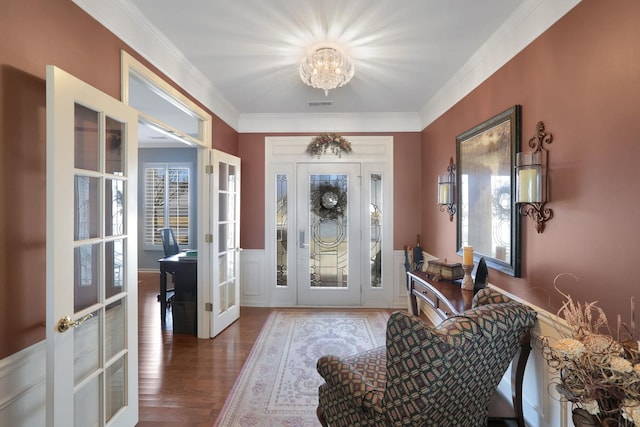 foyer with visible vents, ornamental molding, wood finished floors, french doors, and wainscoting