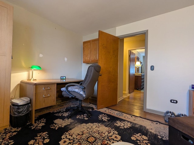 office with built in desk, baseboards, and wood finished floors