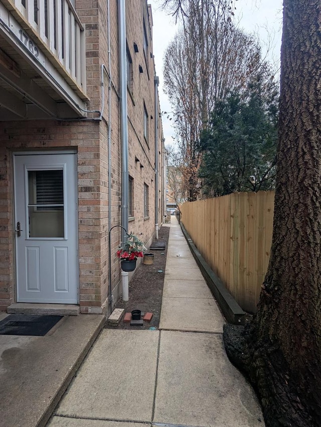 view of side of property featuring brick siding and fence