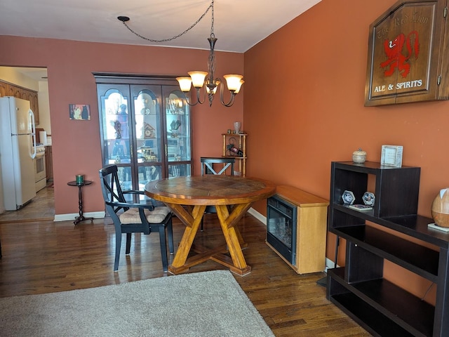 dining area featuring baseboards, dark wood-type flooring, and an inviting chandelier