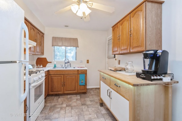 kitchen with white appliances, ceiling fan, a sink, stone finish floor, and under cabinet range hood