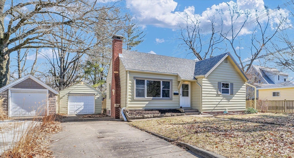view of front facade with an outbuilding, a chimney, a shingled roof, entry steps, and a garage